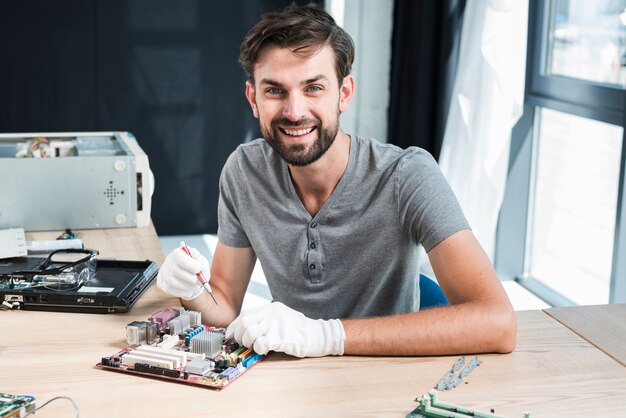 Ritratto di un tecnico maschio sorridente che lavora alla scheda madre del computer