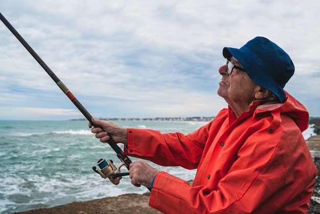 Ritratto di un uomo anziano che pesca in mare, godersi la vita. Concetto di pesca e sport.