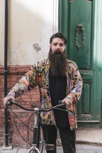 Ritratto di un uomo barba con la sua bicicletta guardando la fotocamera