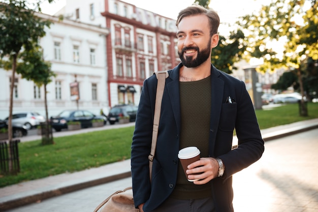 Ritratto di un uomo barbuto sorridente che beve caffè
