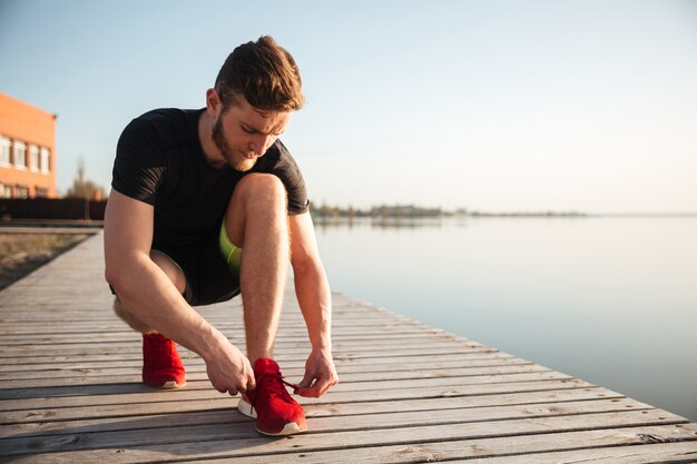 Ritratto di un uomo che lega i lacci delle scarpe sulla scarpa sportiva