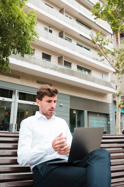 Ritratto di un uomo d'affari che esamina seriamente il computer portatile davanti a costruzione