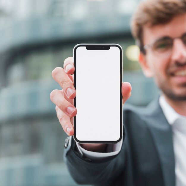 Ritratto di un uomo d&#39;affari che mostra il telefono cellulare dello schermo bianco verso la macchina fotografica