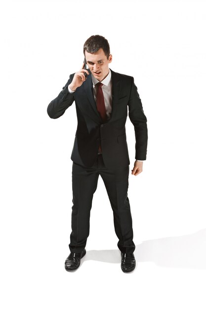 Ritratto di un uomo d'affari con la faccia molto seria e parlando al telefono