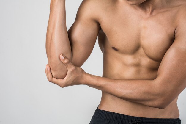 Ritratto di un uomo di muscolo che ha dolore del gomito isolato su fondo bianco