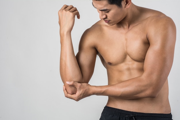 Ritratto di un uomo di muscolo che ha dolore del gomito isolato su fondo bianco