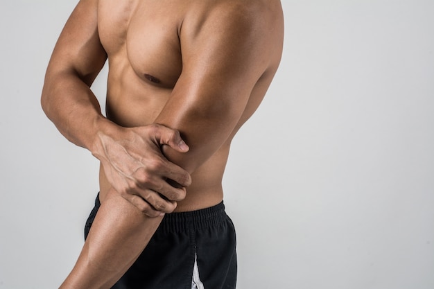 Ritratto di un uomo di muscolo che ha dolore del gomito isolato su fondo bianco
