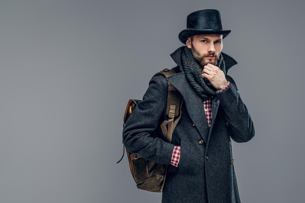 Ritratto di un uomo elegante vestito con una giacca grigia e un cappello a cilindro isolato su sfondo grigio.