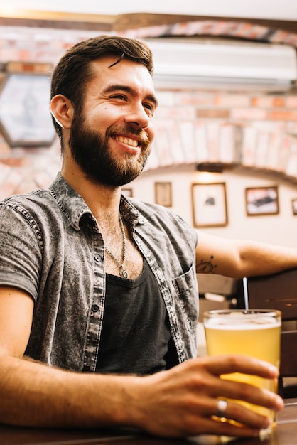 Ritratto di un uomo felice che beve birra nel bar