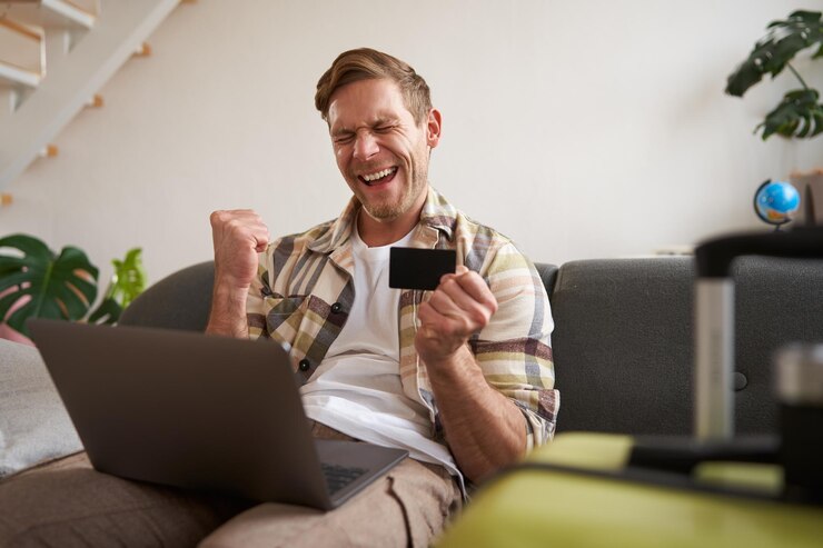 Foto gratuito ritratto di un uomo in vacanza che guarda la sua carta di credito, compra biglietti online, prenota un hotel su
