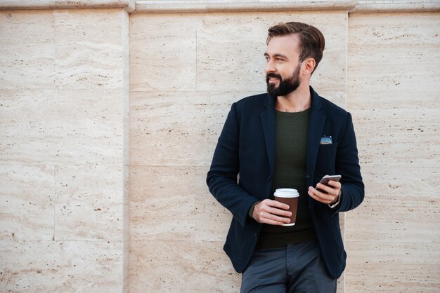 Ritratto di un uomo sorridente bello che tiene tazza di caffè