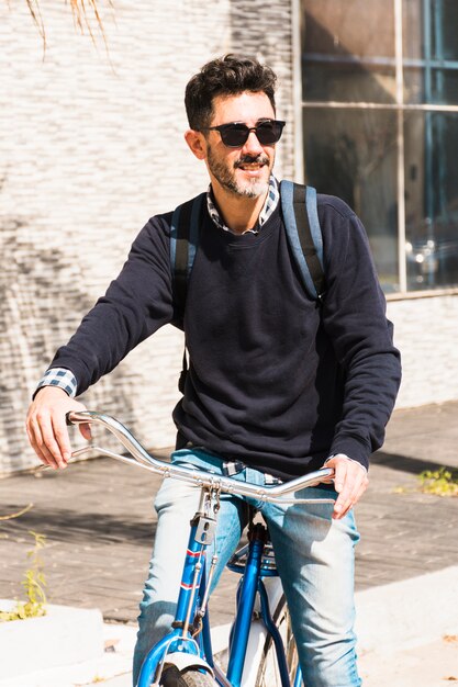 Ritratto di un uomo sorridente che indossa occhiali da sole a cavallo sulla sua bicicletta