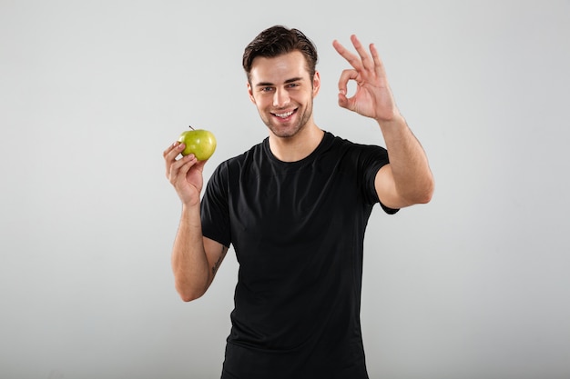 Ritratto di un uomo sorridente felice che tiene mela verde