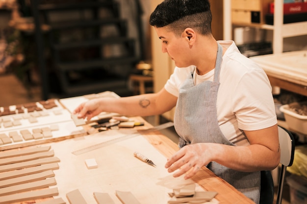 Ritratto di un vasaio femminile che sistema le mattonelle dell&#39;argilla sulla tavola di legno nell&#39;officina