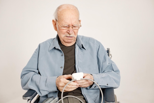 Ritratto di un vecchio su una sedia a rotelle isolato su uno sfondo bianco