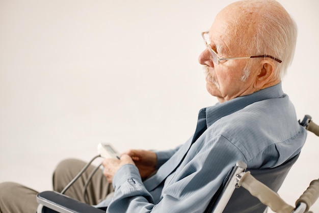 Ritratto di un vecchio su una sedia a rotelle isolato su uno sfondo bianco
