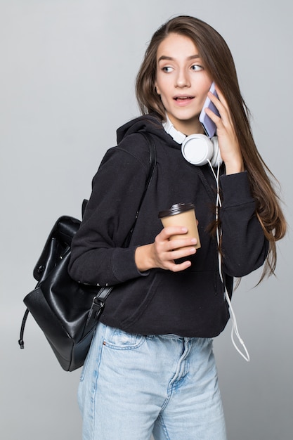 Ritratto di un womantalking su un telefono cellulare isolato sul muro bianco