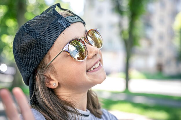 Ritratto di una bambina alla moda in occhiali da sole all'aperto.