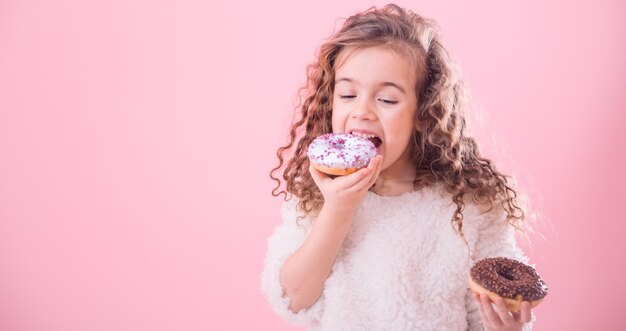 Ritratto di una bambina riccia che mangia le ciambelle