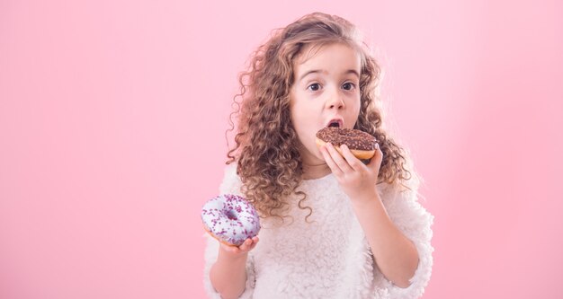 Ritratto di una bambina riccia che mangia le ciambelle