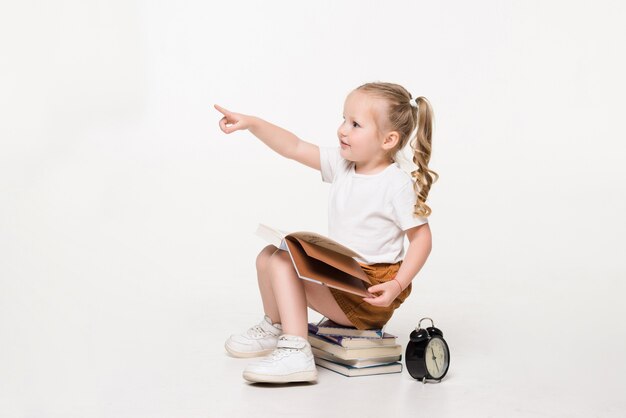 Ritratto di una bambina seduta su una pila di libri ..