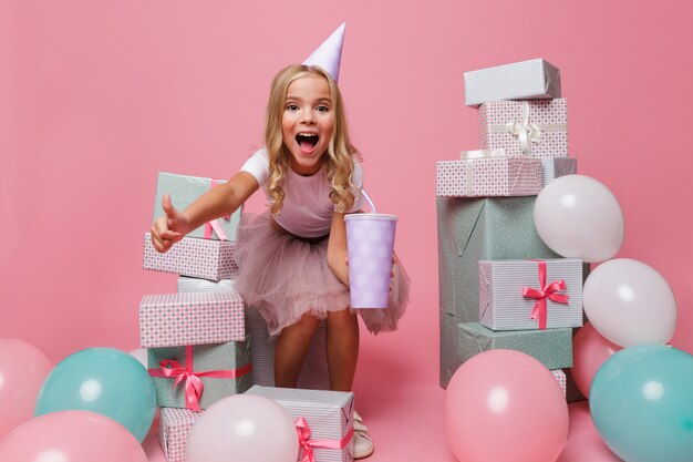 Ritratto di una bambina sorpresa in un cappello di compleanno