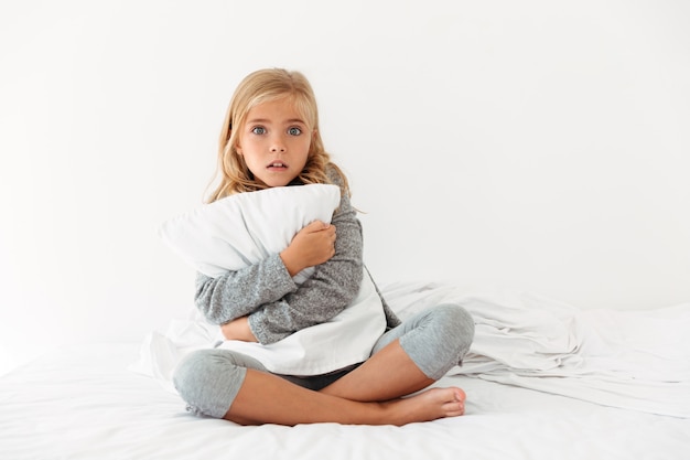 Ritratto di una bambina spaventata che abbraccia cuscino