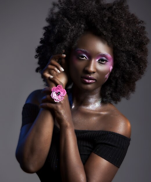 Ritratto di una bella donna afro-americana con un bel trucco che indossa un anello di fiori