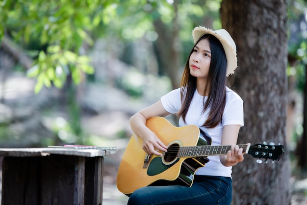 Ritratto di una bella ragazza suonare la chitarra con la scrittura in natura