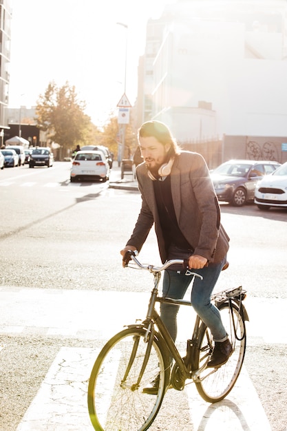 Ritratto di una bicicletta di guida dell&#39;uomo sulla strada di città al sole