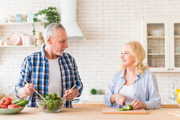 Ritratto di una coppia senior che prepara l&#39;insalata in cucina