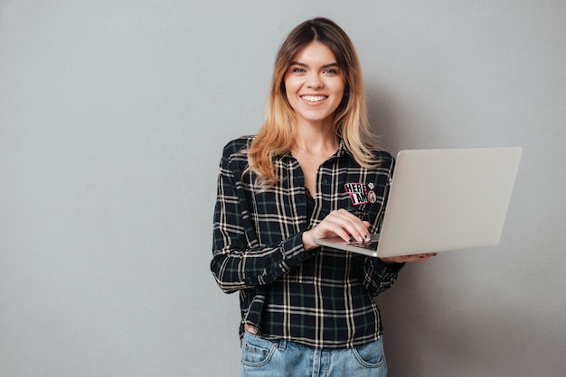 Ritratto di una donna allegra felice che per mezzo del computer portatile