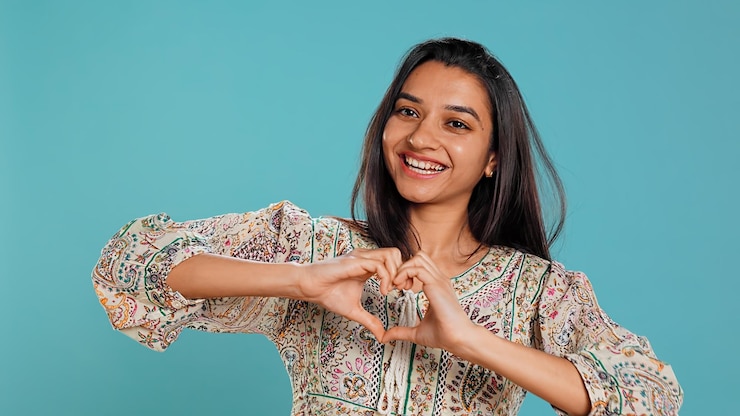 Foto gratuito ritratto di una donna amorevole sorridente che fa un gesto a forma di simbolo del cuore