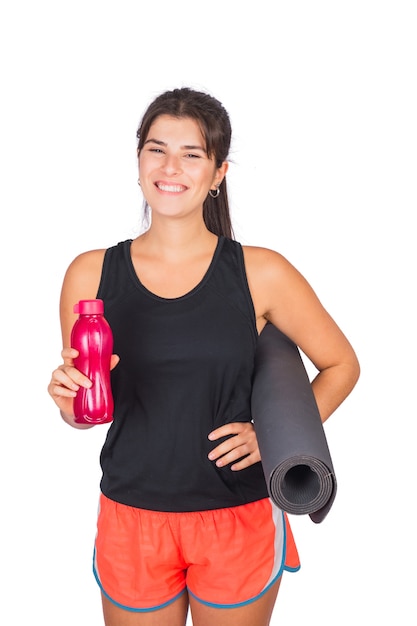 Ritratto di una donna atletica che tiene un matt di yoga e una bottiglia di acqua.