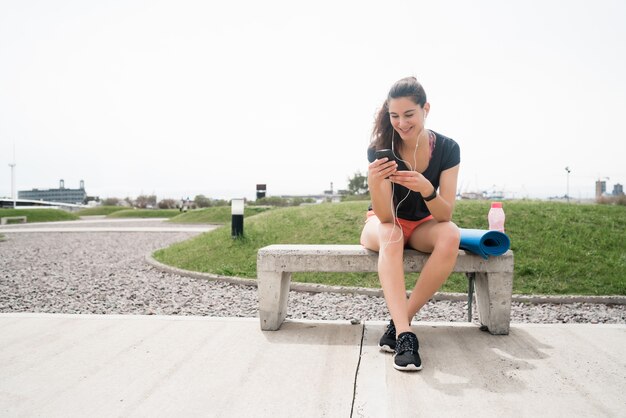 Ritratto di una donna atletica utilizzando il suo telefono cellulare in una pausa dalla formazione. Stile di vita sportivo e salutare.