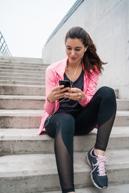 Ritratto di una donna atletica utilizzando il suo telefono cellulare in una pausa dalla formazione. Stile di vita sportivo e salutare.