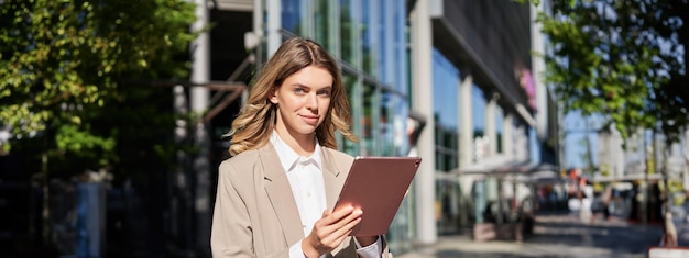 Ritratto di una donna aziendale che legge le notizie sul suo tablet digitale mentre si reca in ufficio