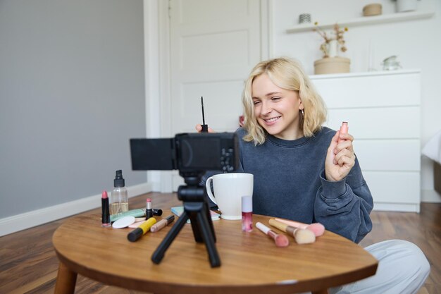 Ritratto di una donna bionda sorridente registra un vlogger di lifestyle o un truccatore che registra un video