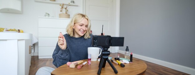 Ritratto di una donna bionda sorridente registra un vlogger di lifestyle o un truccatore che registra un video