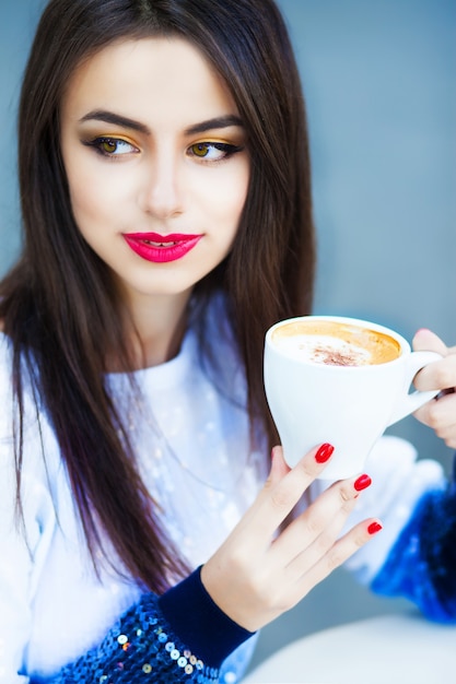 Ritratto di una donna con i capelli lunghi che beve un caffè