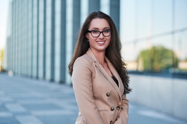 Ritratto di una donna d'affari di successo con un sorriso affascinante in posa per strada con un'architettura interessante sullo sfondo.