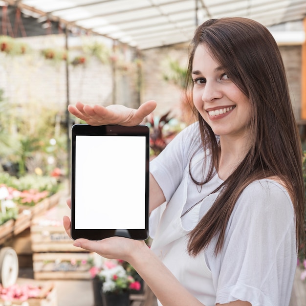 Ritratto di una donna felice che mostra compressa digitale con schermo bianco vuoto