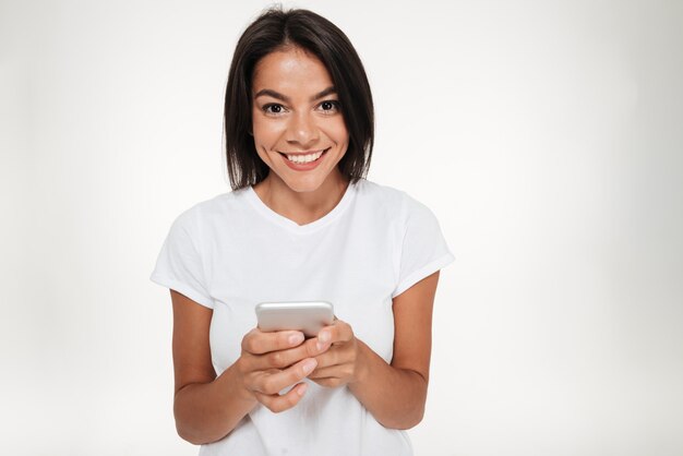 Ritratto di una donna felice del brunette che tiene telefono mobile