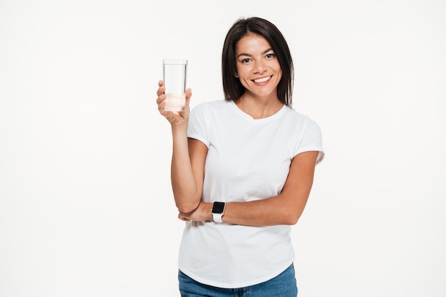 Ritratto di una donna in buona salute sorridente che giudica di vetro con acqua