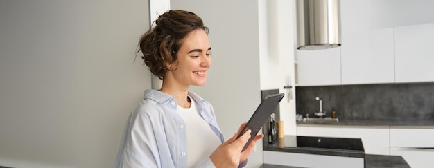 Ritratto di una donna sorridente che guarda il suo tablet digitale, legge messaggi e guarda video online