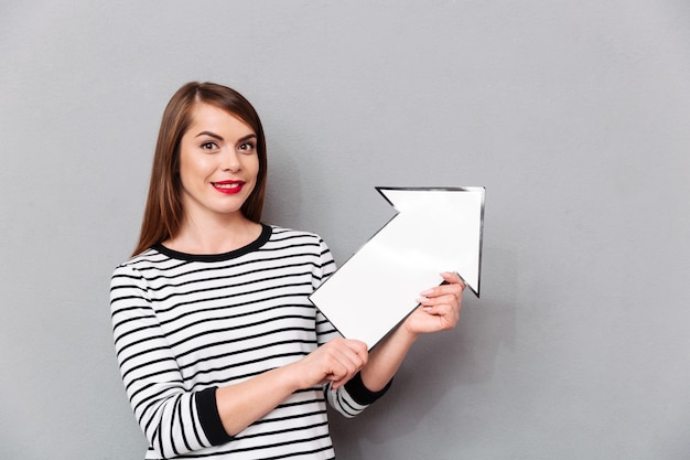 Ritratto di una donna sorridente che indica la freccia di carta in su