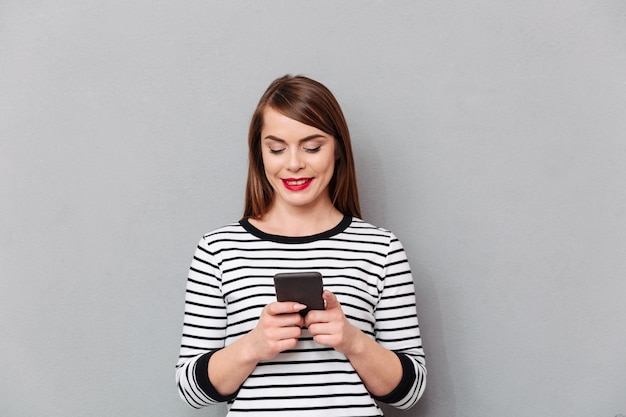 Ritratto di una donna sorridente che manda un sms sul telefono cellulare