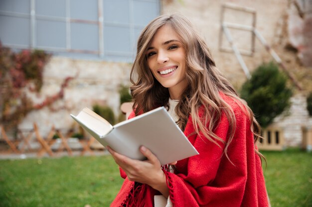 Ritratto di una donna sorridente che si siede con un libro