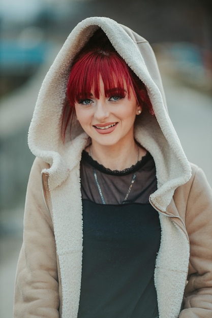 Ritratto di una donna sorridente dai capelli rossi con la frangia che indossa un caldo cappotto invernale