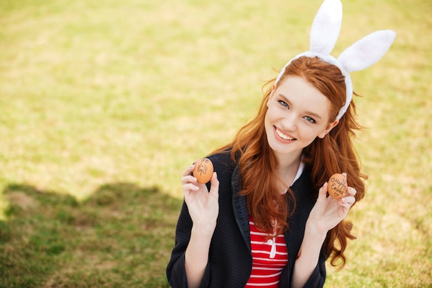 Ritratto di una donna sorridente della testa rossa che indossa le orecchie del coniglietto